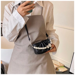 Detailed shot of black pleated bag featuring large pearl chain and silver heart charm