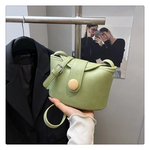 Detail of avocado green soft leather crossbody bag with wooden buckle decoration