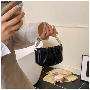 Detail of pleated cloud handbag featuring pearl and silver chain handle with metallic hooks