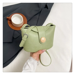 Close-up of mint green leather bag featuring a round wood-grain buckle and strap