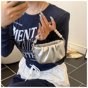 Detail of silver metallic pleated handbag featuring faux pearl handle and metal chain