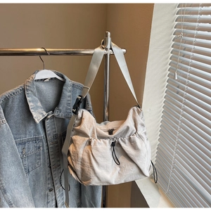 Detail of light grey nylon messenger bag with drawstring pocket and wide shoulder strap