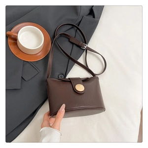 Detail of a vintage dark brown soft leather crossbody bag with a round buckle