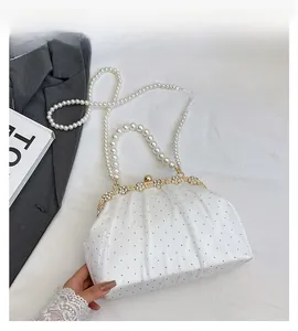 Détail d'une pochette de soirée plissée blanche avec anse perle et boucle en cristal