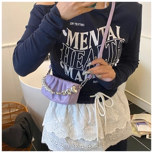 Detail of lavender pleated handbag featuring faux pearl strap and silver heart charm