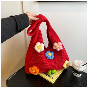 Gros plan d'un sac cabas en tricot rouge avec des fleurs au crochet colorées et texture