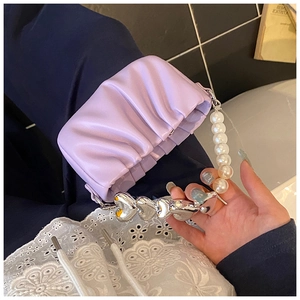 Detailed shot of lavender pleated handbag featuring pearl and silver heart metal strap