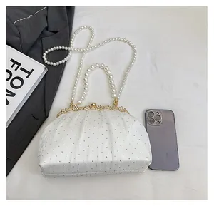 Sac de soirée blanc froncé avec anse en perles et strass à côté d'un smartphone