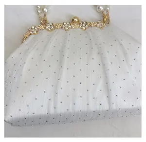 Détails d'une pochette nuage blanche avec poignée en perles et strass scintillants