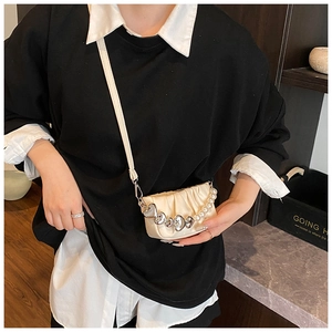 Detail of cream pleated mini bag with silver heart chain and pearl accents