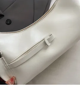 Détail du sac croissant blanc crème montrant la texture lisse et le zip argenté