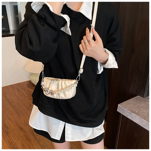 Detail of cream pleated mini bag featuring pearl chain and silver heart pendant