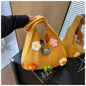 Détail d'un sac tricoté jaune avec fleurs 3D se reflétant dans un miroir de beauté