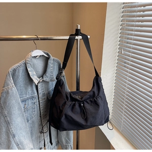 Detail of black nylon crescent crossbody bag with drawstring design and adjustable strap