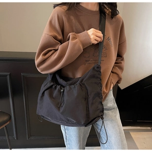 Detailed close-up of a black drawstring canvas bag with adjustable buckles and strap