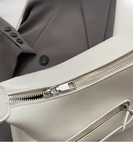 Détail de la fermeture éclair argentée lisse et poche sur le sac sous le bras blanc cassé
