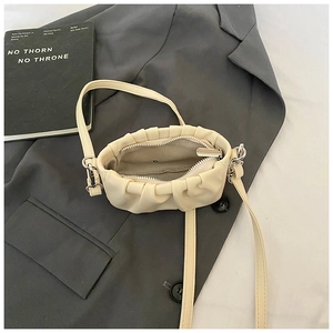 Close-up of beige pleated cloud bag with soft faux leather texture and zipper closure