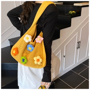 Détail du sac tricoté jaune avec fleurs au crochet 3D colorées sur l'épaule