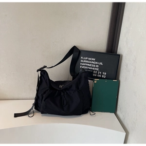 Detail of durable black nylon crossbody bag featuring adjustable strap and drawstring closure