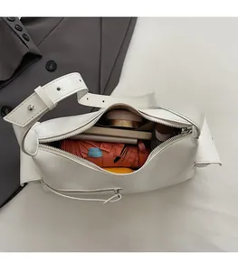 Détail montrant la grande capacité du sac à bandoulière en cuir blanc avec des objets
