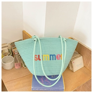 Detailed view of summer embroidery on a mint green woven tote bag with slim straps