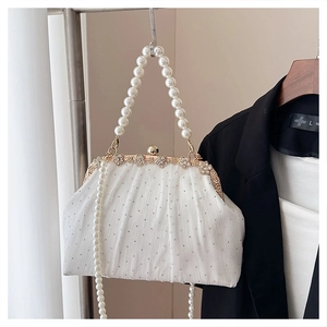 Détail d'un sac de soirée blanc plissé avec perles, strass et fermoir en métal à fleurs