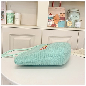 Detail of light green hand-woven tote bag with textured knit and rainbow embroidery