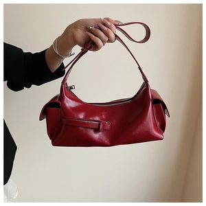 Detail of dark red glossy shoulder bag featuring vintage textures and zipper buckles
