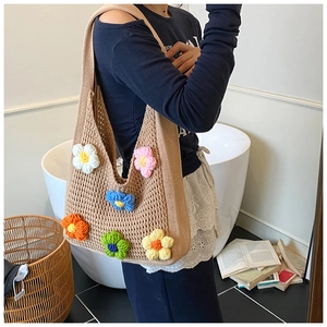 Détail du sac fourre-tout en tricot avec fleurs 3D porté par un mannequin en intérieur