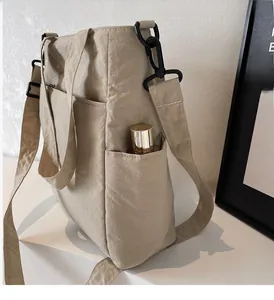 Detail of khaki nylon tote bag showing side pocket functionality with a water bottle