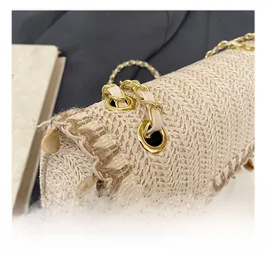 Détail du sac en paille beige avec tissage en V et chaîne dorée avec lanière en cuir rose