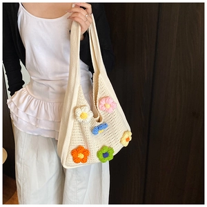 Détail d'un sac bandoulière tricoté main avec fleurs crochetées 3D sur maille beige