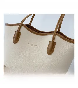 Close-up of contrast tote bag featuring creamy pebble leather and dark brown trim