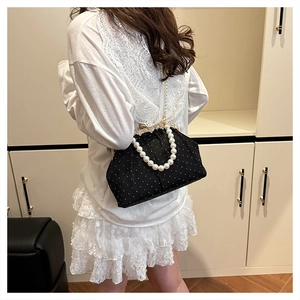 Détail d'un sac à main noir à pois avec fermoir en strass dorés et bandoulière en perles