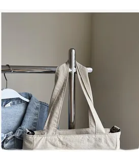 Detail of the reinforced stitching on the beige tote bag handle with metal D-ring attachment
