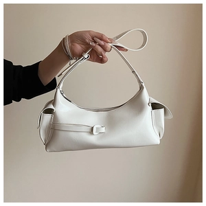 Detail of a beige baguette bag with side pockets and smooth synthetic leather texture