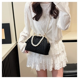 Gros plan du sac à main vintage à pois avec une poignée élégante en perles blanches