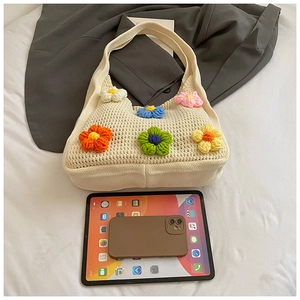 Détail d'un sac cabas en maille fleurie à côté d'une tablette montrant la taille et texture