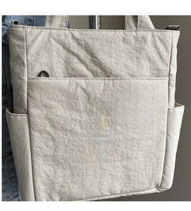 Close-up of beige canvas tote bag with wrinkled texture and functional front pocket