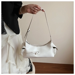 Close-up detail of white faux leather baguette bag with side pocket and decorative zipper
