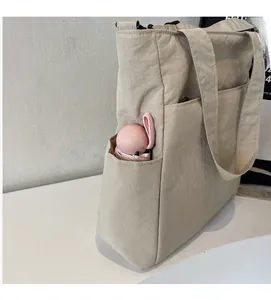 Detail of canvas tote bag side pocket holding a folding umbrella for storage space