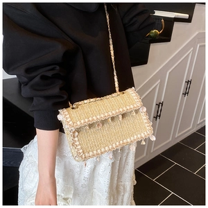 Détail du sac en paille tissée avec franges, breloques en résine et bandoulière chaîne