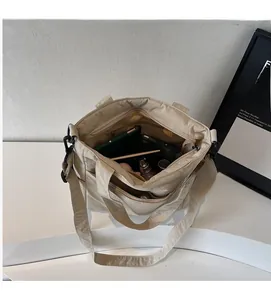 Detail view of spacious beige tote bag interior showing various everyday essentials and gadgets