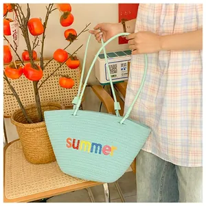 Detail of mint green woven tote with Summer embroidery and slim shoulder straps