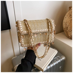 Détail du sac en paille avec bords en dentelle et breloques coquillages style bohème