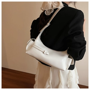 Détail latéral d'un sac hobo blanc porté par un mannequin en blazer noir avec style chic