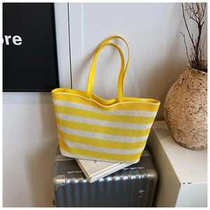 Detail showing the yellow and white woven grid pattern of the large striped tote bag