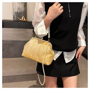 Détail d'une pochette plissée dorée avec bordure en strass et bandoulière en perles