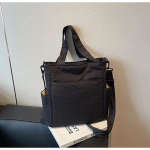 Detailed view of black canvas tote bag with multiple pockets and adjustable strap