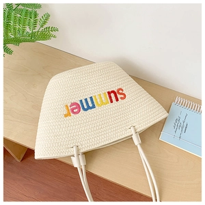 Detail of hand-woven summer tote bag with colorful embroidered summer lettering on a desk